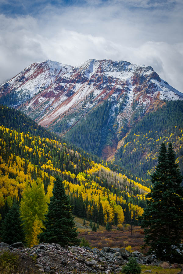 A red mountain with aspens and snow.